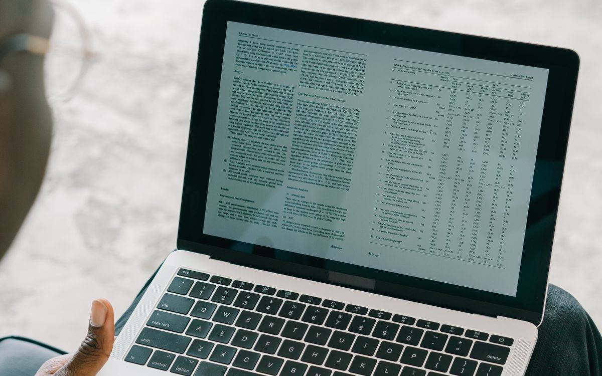 A laptop screen showing a generated document with text and tables ready for review